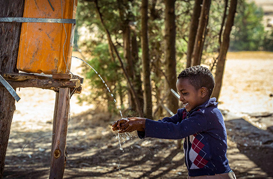 Boy playing in water from fresh water supply